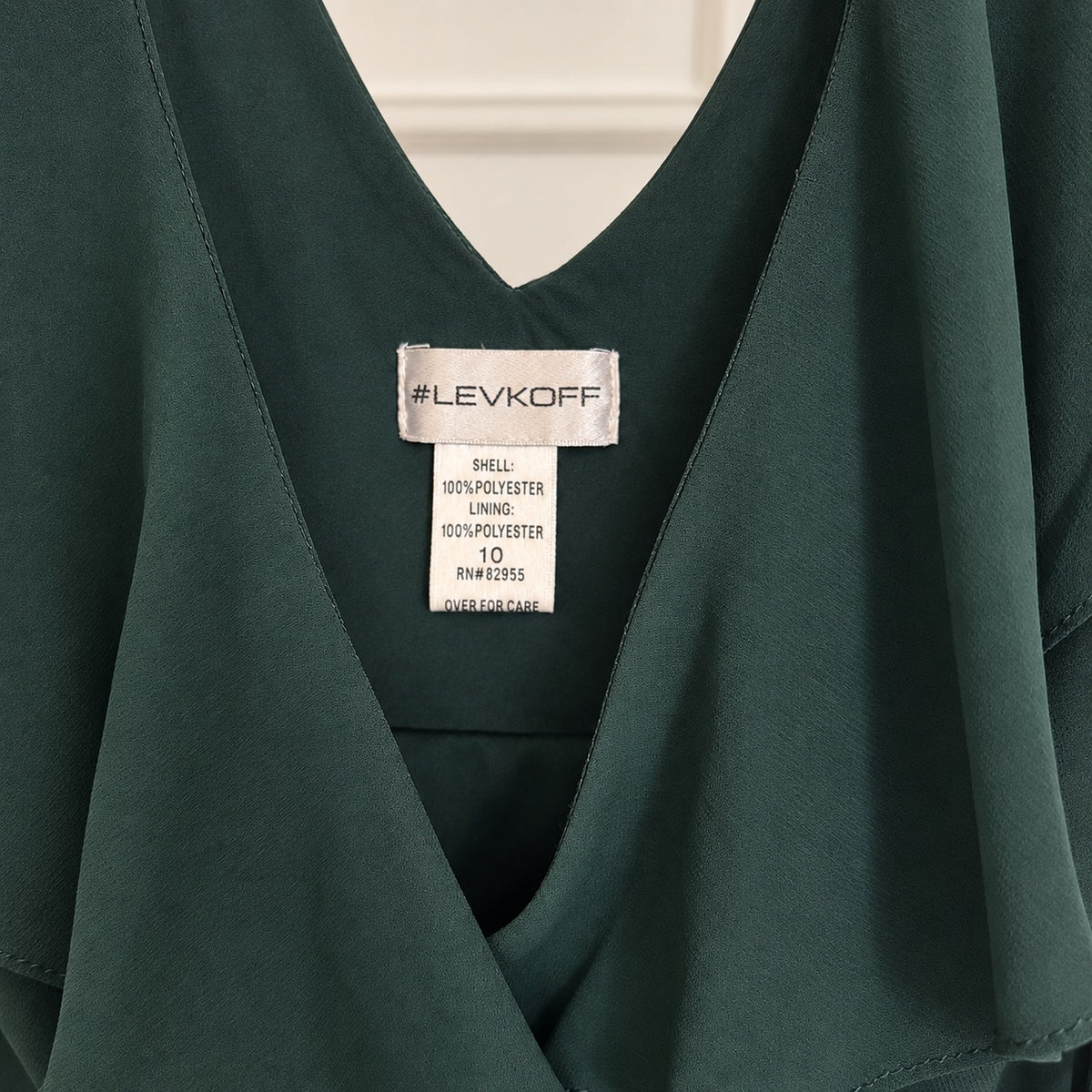 Close-up of a dark green V-neck blouse with a visible Levi's Koff brand label inside the neckline, showing fabric texture and size details.
