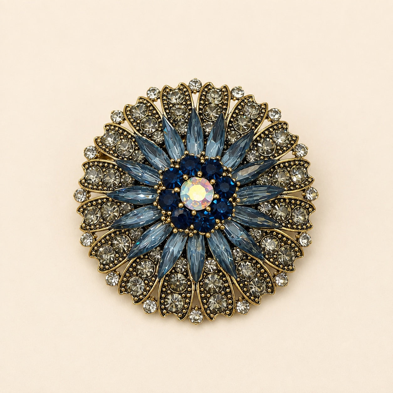 Vintage blue and gold flower brooch with marquise crystals, dark blue accent stones, and clear rhinestone petals on gold metal.