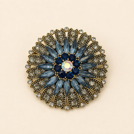 Vintage blue and gold flower brooch with marquise crystals, dark blue accent stones, and clear rhinestone petals on gold metal.
