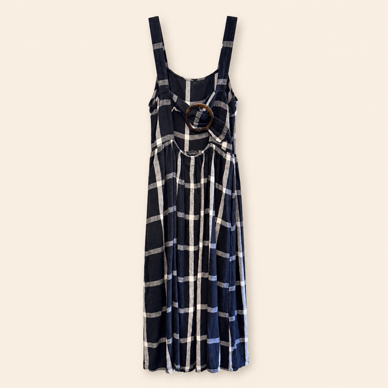 A navy blue plaid midi dress with white and light blue stripes, featuring a keyhole back design with a brown wooden ring accent, shown against a solid cream background.