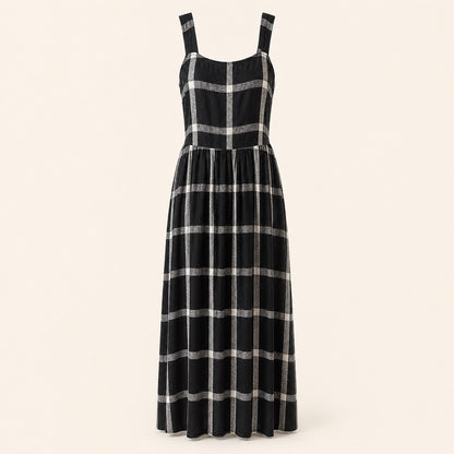 A sleeveless black midi dress with a silver metallic plaid pattern, featuring a structured bodice and wide shoulder straps, shown against a solid light beige background.