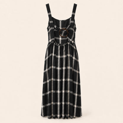 A sleeveless black and white plaid midi dress with a round brown wooden ring detail at the center bust, displayed on a neutral cream background.