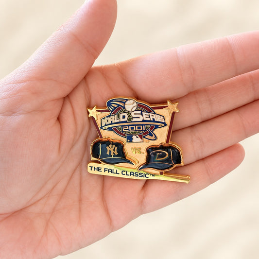 A gold and navy blue enamel pin commemorating the 2007 World Series vs. The Fall Classic, held in a person's hand against a soft beige background.