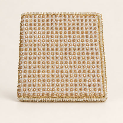 A square beaded clutch bag featuring a grid pattern of cream and gold faux pearls with a matching gold beaded border, set against a solid off-white background.