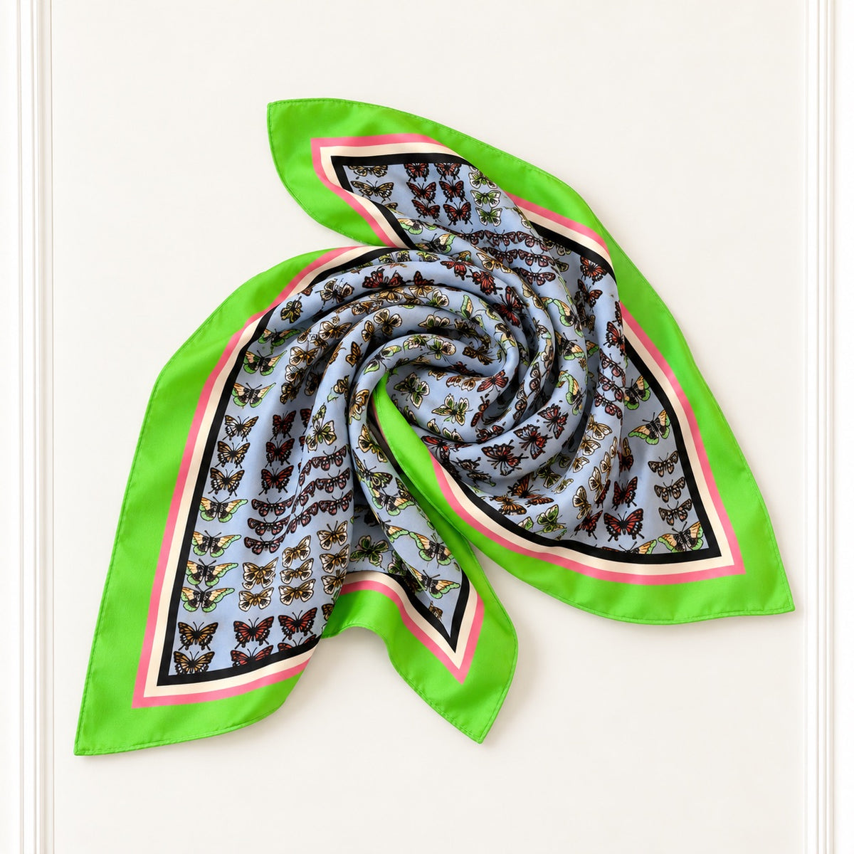 A square silk scarf with a butterfly print, featuring a bright green border, pink and black stripes, and a light blue center with rows of brown and yellow butterflies, arranged in a swirl on a white background.