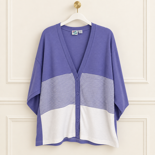 A purple and white color-block knit cardigan with horizontal stripes, hanging on a white hanger against a cream paneled wall.