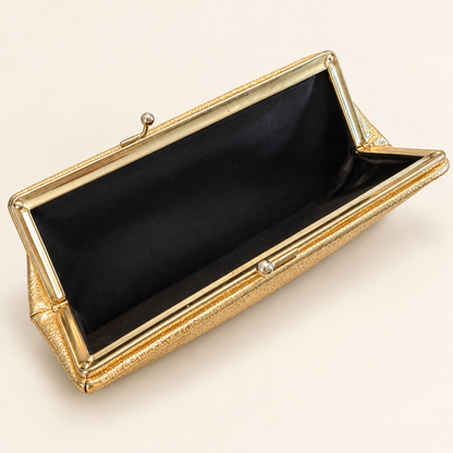 A gold textured clutch bag with a black satin interior, shown open on a light beige background.
