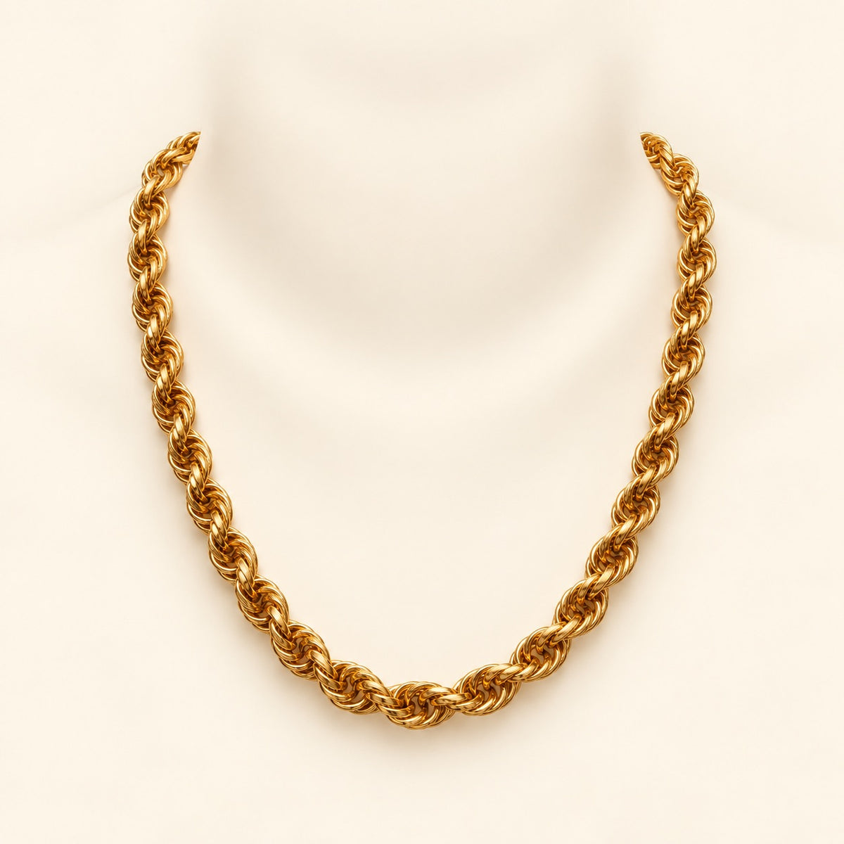 A chunky gold rope chain necklace displayed on a white mannequin neck against a light cream background.