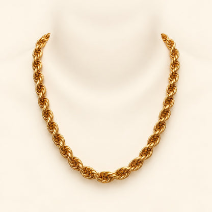 A chunky gold rope chain necklace displayed on a white mannequin neck against a light cream background.