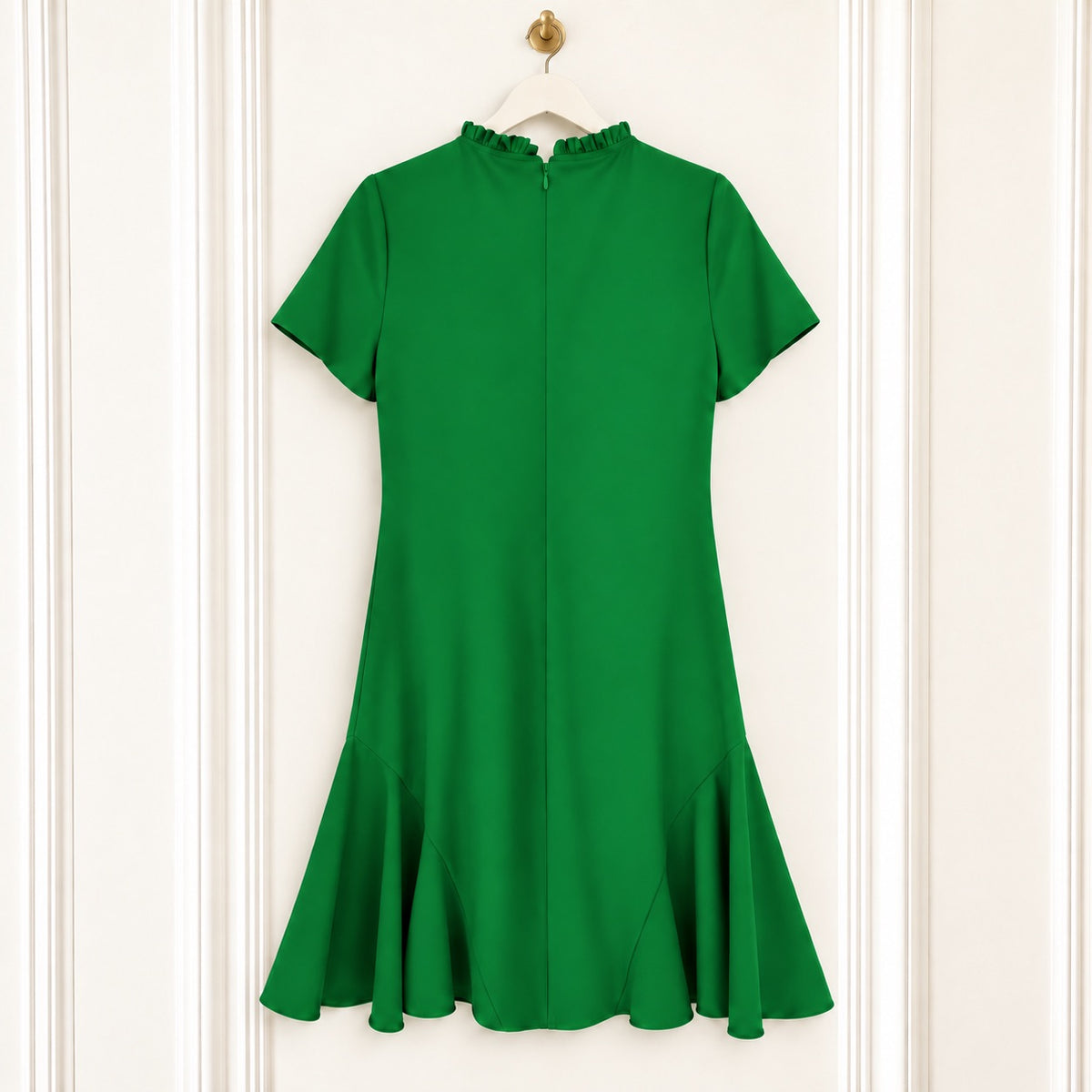 A bright green short-sleeve dress with a high ruffled mock neck and a flared ruffle hem, hanging on a white hanger against a white paneled door.