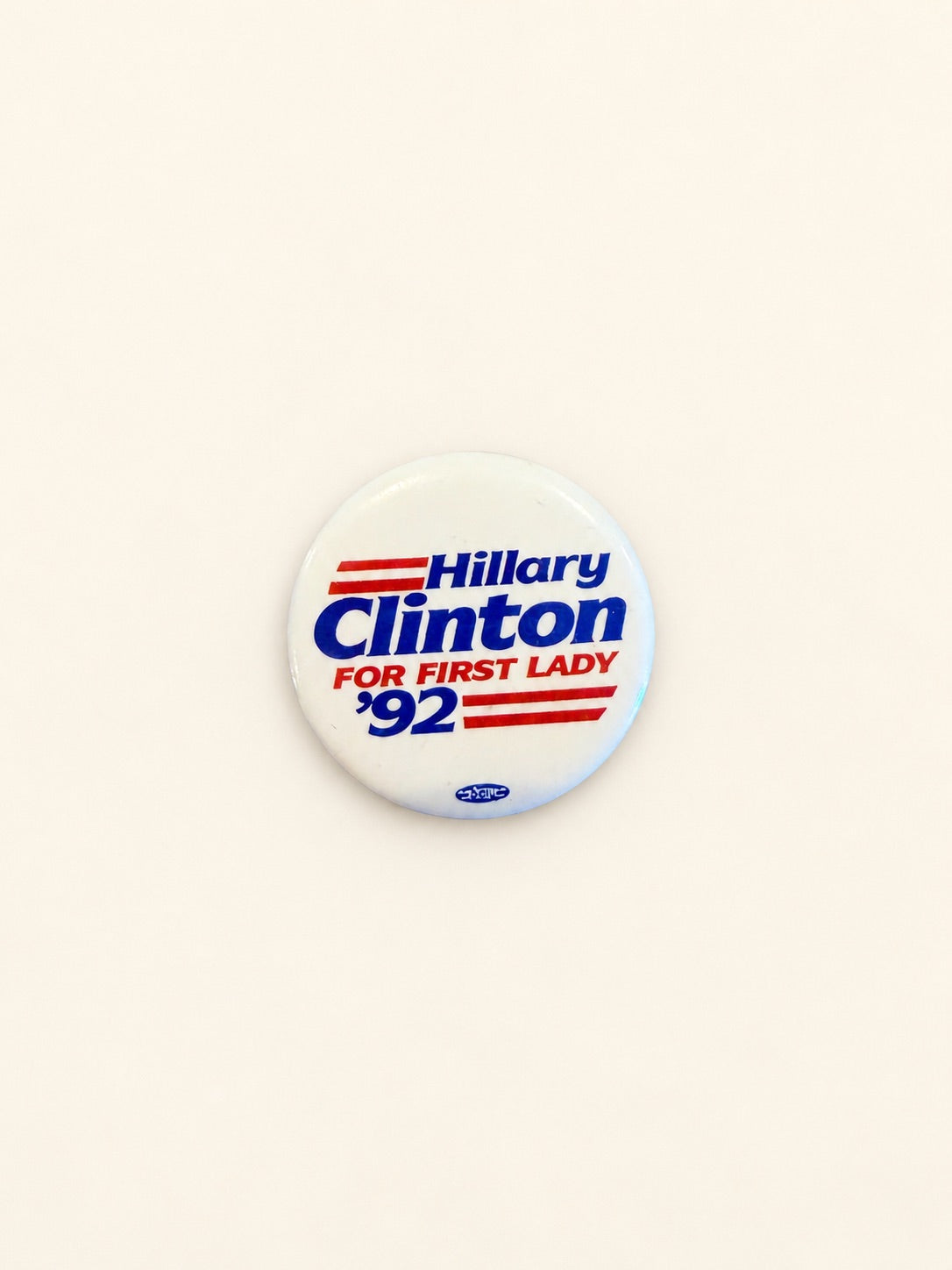 A round white button badge featuring Hillary Clinton '92 campaign text in blue and red, photographed on a plain off-white background.