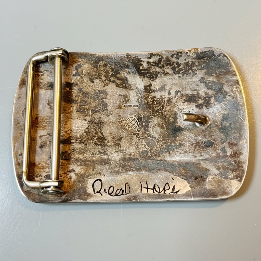 Rust-covered metal object with 'Real Hopi' engraved on a metallic background