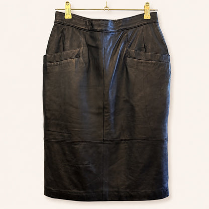 A black leather pencil skirt with two large front patch pockets, hanging from a gold metal hanger with gold clips against a plain off-white background.