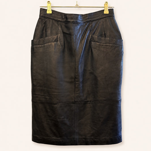 A black leather pencil skirt with two large front patch pockets, hanging from a gold metal hanger with gold clips against a plain off-white background.