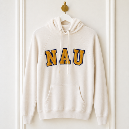 An off-white hooded sweatshirt hanging on a white hanger from a gold wall hook, featuring the letters 'NAU' in gold with a navy blue outline across the chest.