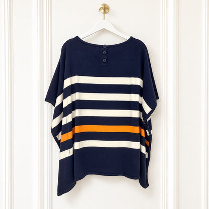 A navy blue short-sleeve tunic top with horizontal cream and orange stripes, hanging on a white hanger against a white paneled door.