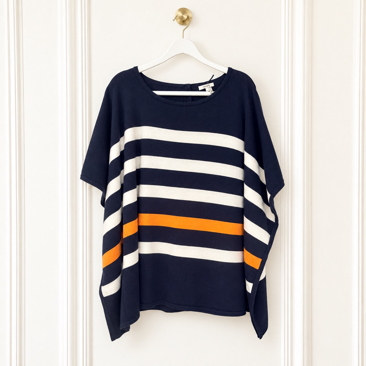 A navy blue short-sleeve top with wide horizontal white and orange stripes, hanging on a white hanger against a white paneled door.