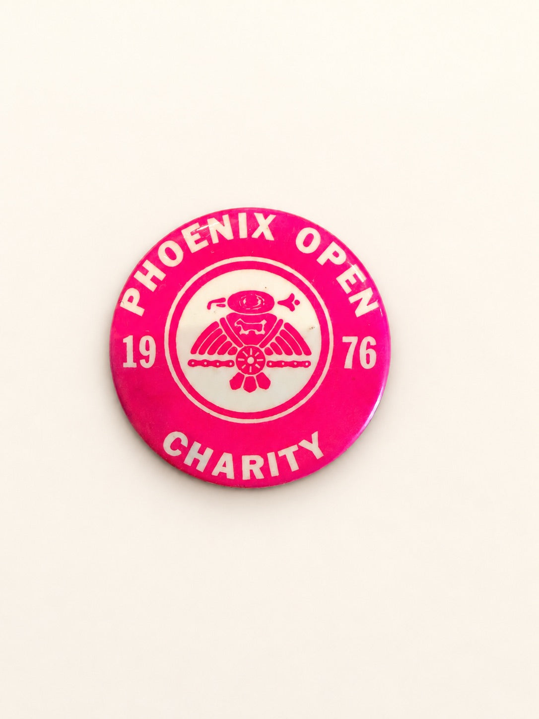 A round pink and white Phoenix Open Charity 1976 pinback button badge, displayed on a clean off-white background.