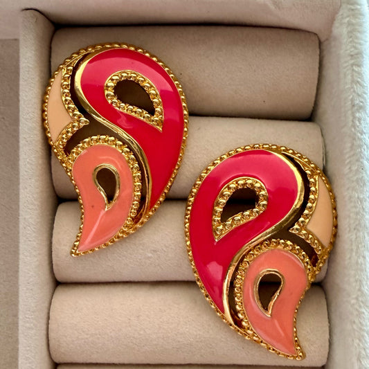 A pair of gold-tone paisley-shaped earrings with glossy pink and peach enamel, displayed in a beige jewelry box.