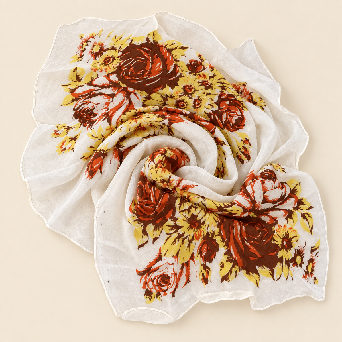 A lightweight white scarf with a vintage floral print featuring large brown and yellow roses, styled in a spiral drape on a solid beige background.