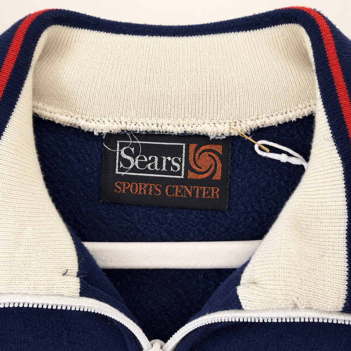 Close-up of a vintage Sears Sports Center quarter-zip pullover sweater collar, showing navy blue fleece, cream ribbed knit trim with red stripes, and the original Sears brand label.