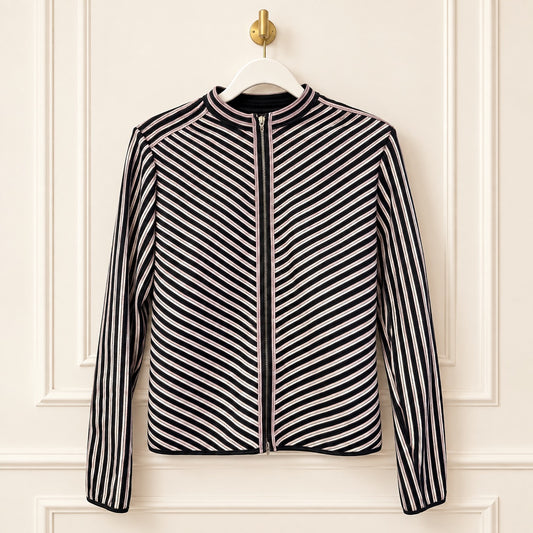 A women's zip-front jacket with a stand collar, featuring diagonal black and white stripes on the body and sleeves, hanging on a white hanger against a cream-colored paneled wall.