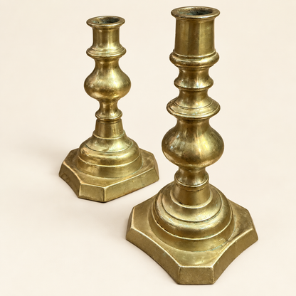 A pair of vintage brass candlesticks with hexagonal bases, shown on a plain light beige background.