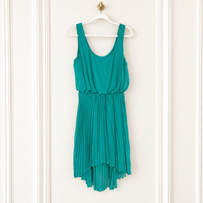 A teal green sleeveless dress with a pleated skirt, hanging on a white hanger against a white paneled door.