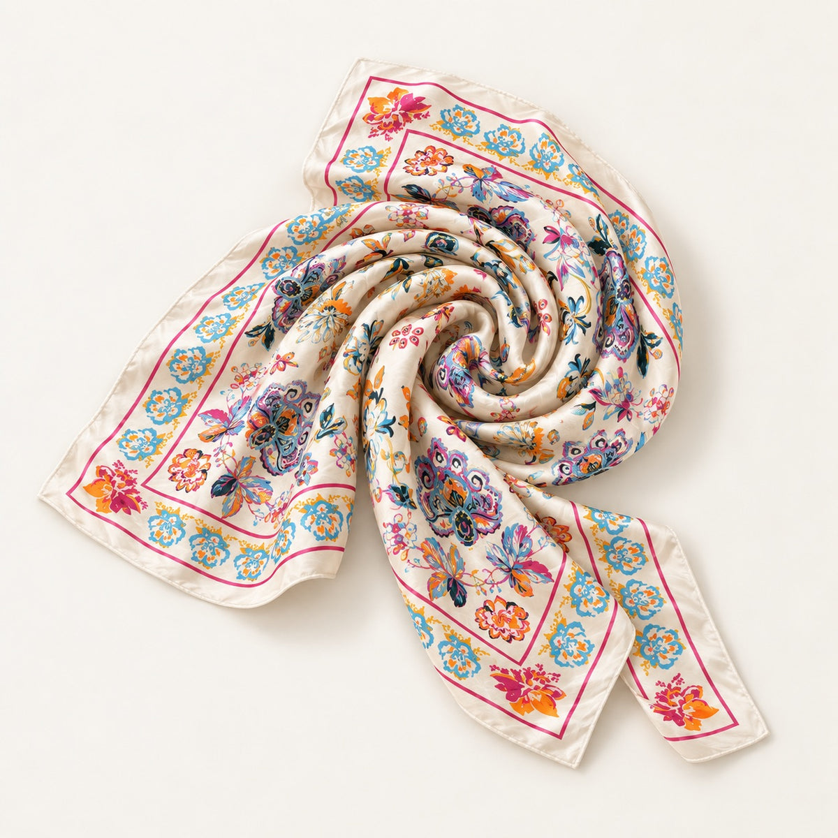 A square silk scarf with a colorful floral and butterfly pattern on a cream background, styled in a spiral on a light beige background.