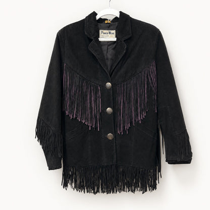 A black suede fringe jacket with purple fringe accents on the chest, hanging on a white hanger against a plain white wall. The brand label reads 'Pierce Wear'.