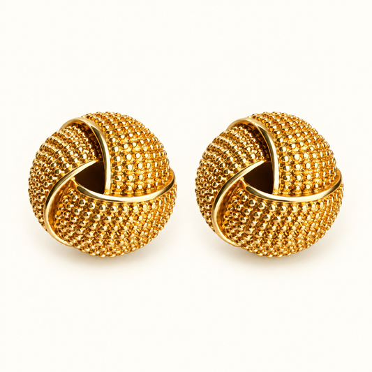 A pair of gold-toned knot-style earrings with a textured, beaded surface, displayed on a clean white background.