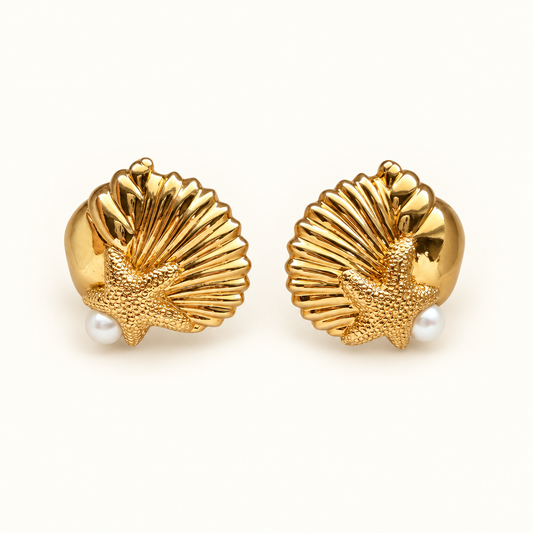 A pair of gold shell and starfish stud earrings with small white pearl accents, displayed on a clean off-white background.