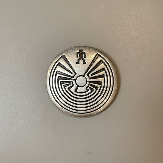 Metallic pin with a central design on a textured surface