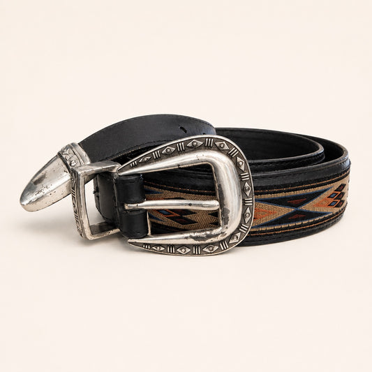 A western-style leather belt with a black strap, a silver-toned engraved buckle, and a woven geometric pattern in brown, orange, and blue, displayed on a light beige background.